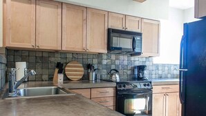 A kitchen with wooden cabinets, a microwave, a stove, and a sink. - Bluebird Day - Casa Sol: Cozy 2BR townhome in Bend, OR, featuring two King beds and a hot tub. (Bend)