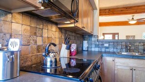 Una cocina con estufa, horno y hervidor sobre la encimera.