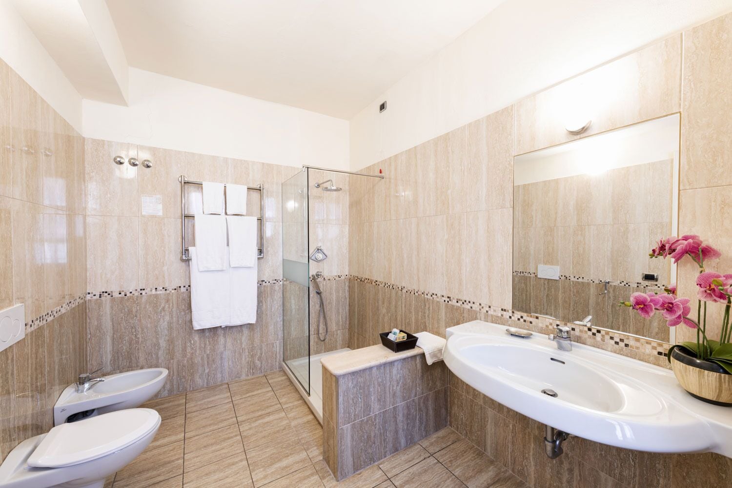 A modern bathroom with two sinks, a shower, and a large mirror.