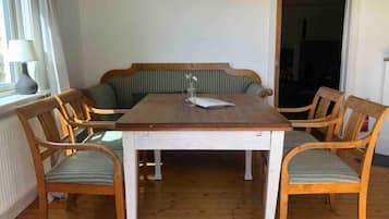 Ett matrum med ett träbord, sex stolar, en bänk och ett fönster med en lampa.