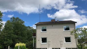 Een tweelaags huis met een bakstenen gevel, schoorsteen en schotelantenne.