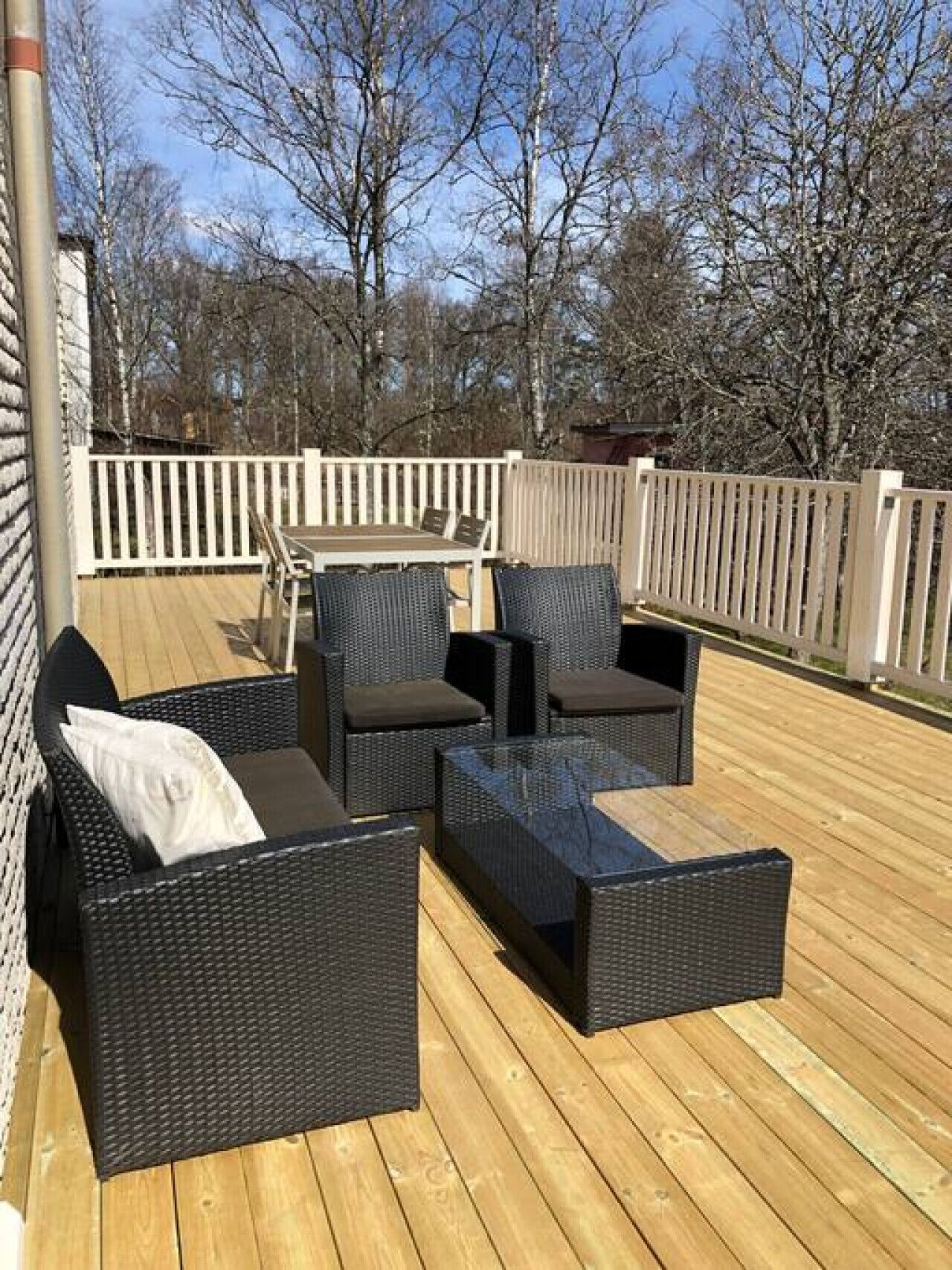 Une terrasse dotée de meubles en osier, notamment des canapés et une table basse.