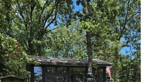 Eine rustikale Holzhütte mit einer Steinterrasse, Sitzgelegenheiten im Freien und einem kleinen Garten.
