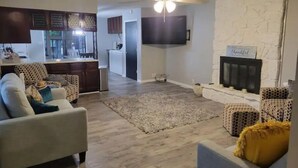 Ein Wohnzimmer mit Kamin, einer Couch und einem an der Wand befestigten Fernseher.