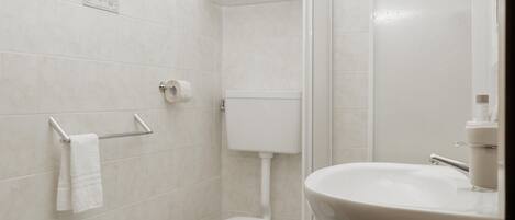 Un baño moderno con inodoro, bidé, lavamanos y cabina de ducha de vidrio.
