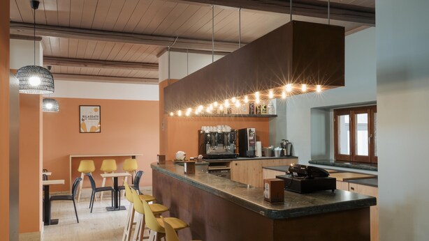 Un área de bar moderna con una barra alargada, taburetes y una máquina de café.