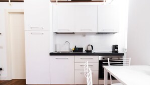 Una cuina moderna amb armaris blancs, tauleig negre i taula de dinar blanca.