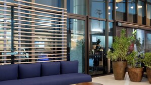 Een moderne lobby met een blauwe bank, een houten lattenwand, grote ramen en potplanten.
