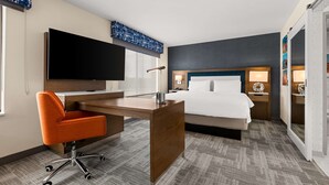A hotel room with a bed, desk, chair, flat-screen TV, bedside lamps, and a large window. - Hampton Inn & Suites Bessemer Birmingham (Bessemer)