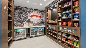 A snack bar with shelves stocked with various snacks and a refrigerated display case. - Hampton Inn & Suites Bessemer Birmingham (Bessemer)