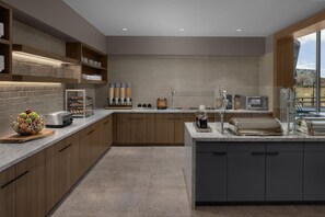 A modern kitchen with a central island, built-in shelves, and a variety of appliances. - Homewood Suites By Hilton Grand Prairie At Epiccentral (Grand Prairie)