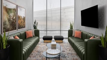 A modern living room with a green sofa set, a glass coffee table, and a large window.