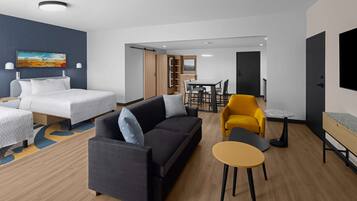 Una habitación de hotel moderna con cama, sofá, mesa de comedor y sillas.