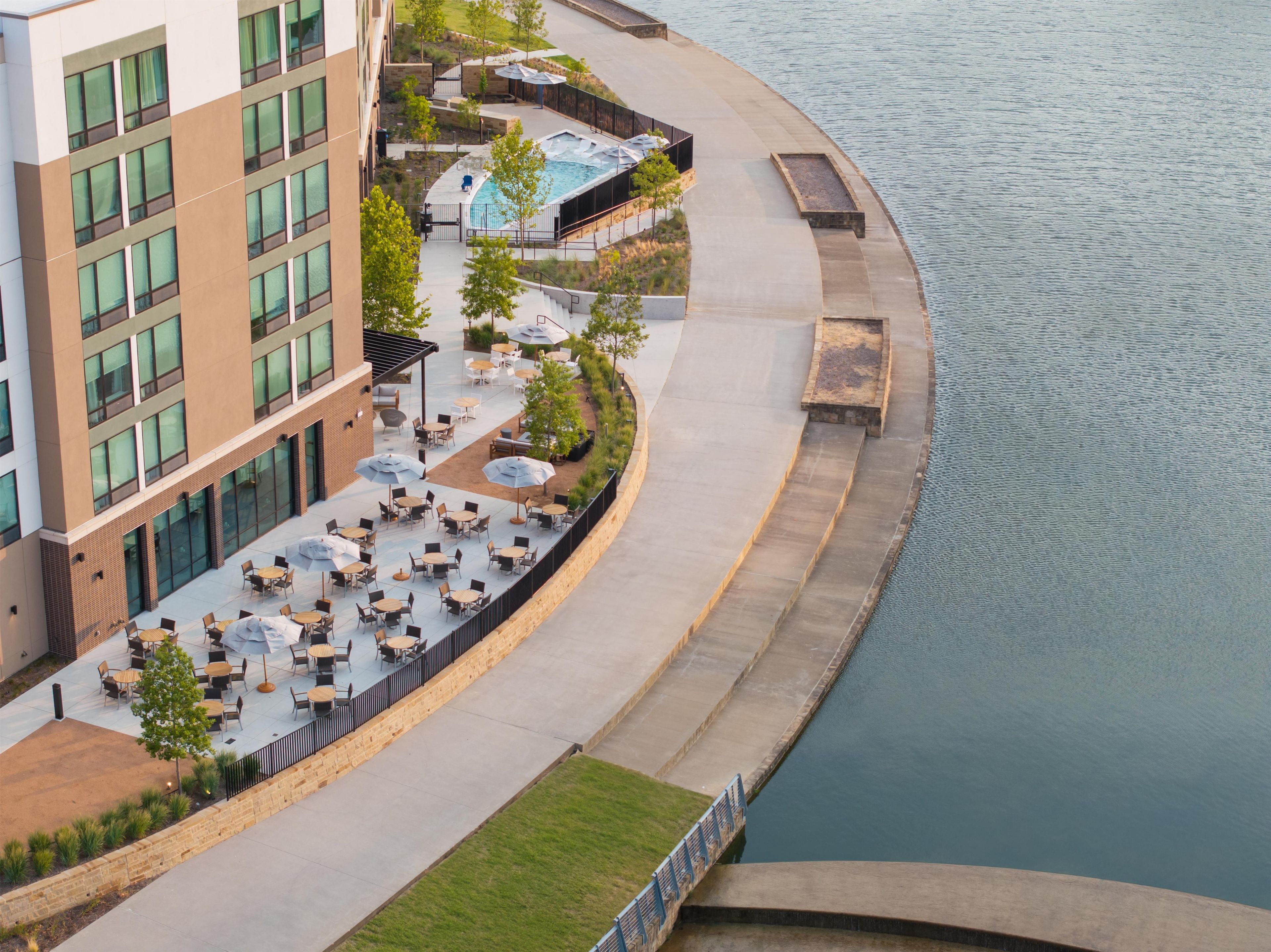 A waterfront hotel with outdoor seating, a pool, and a view of the water.