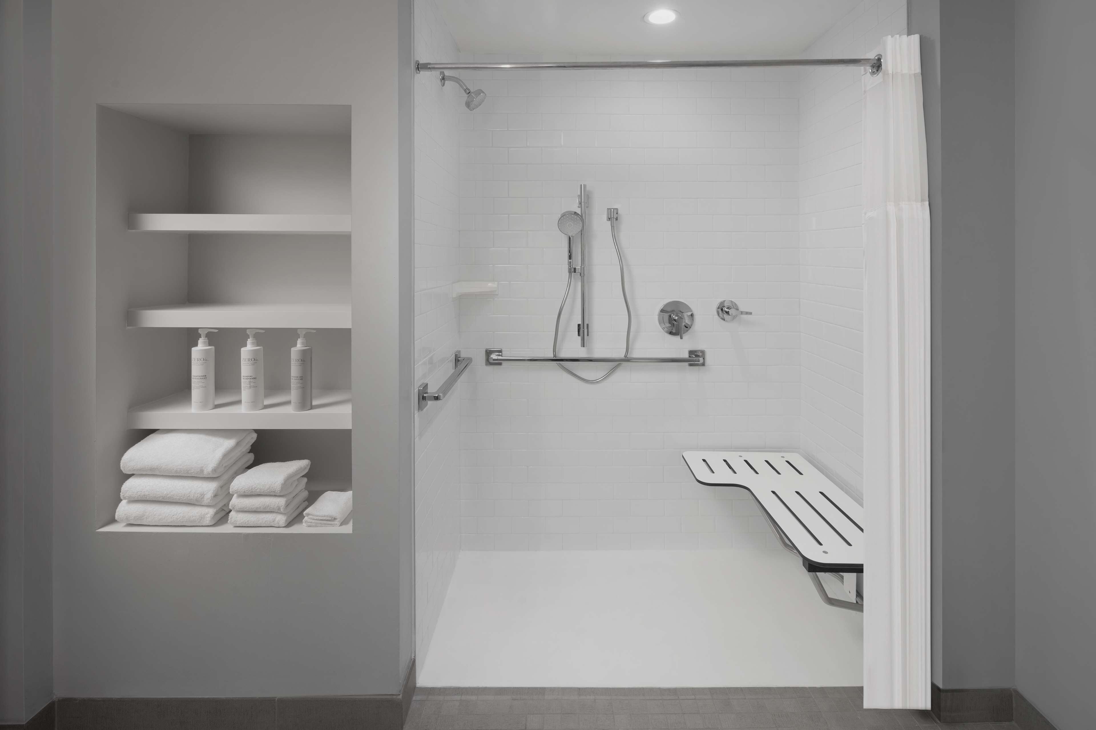 Un baño moderno con ducha, inodoro y un estante con artículos de aseo.