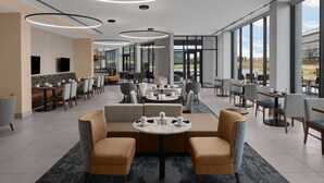Um hall de hotel espaçoso com área de estar central, amplas janelas com vista e design moderno.