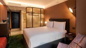 A hotel room with a large bed, a small table, a chair, and a separate seating area with a couch.
