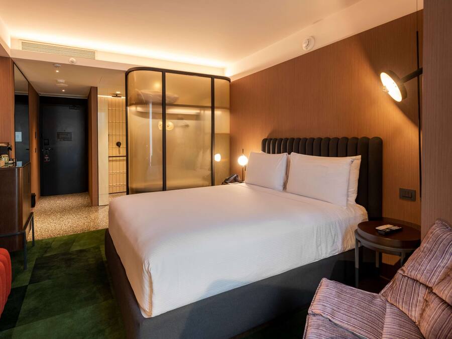 A hotel room with a large bed, a small table, a chair, and a separate seating area with a couch.