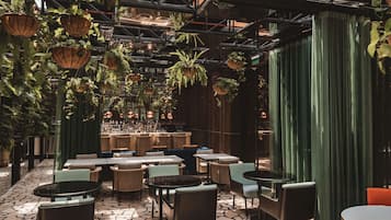 Un restaurante con plantas colgantes, mesas y sillas.