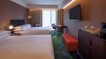 A hotel room with two beds, a desk, a chair, a TV, and a minibar.