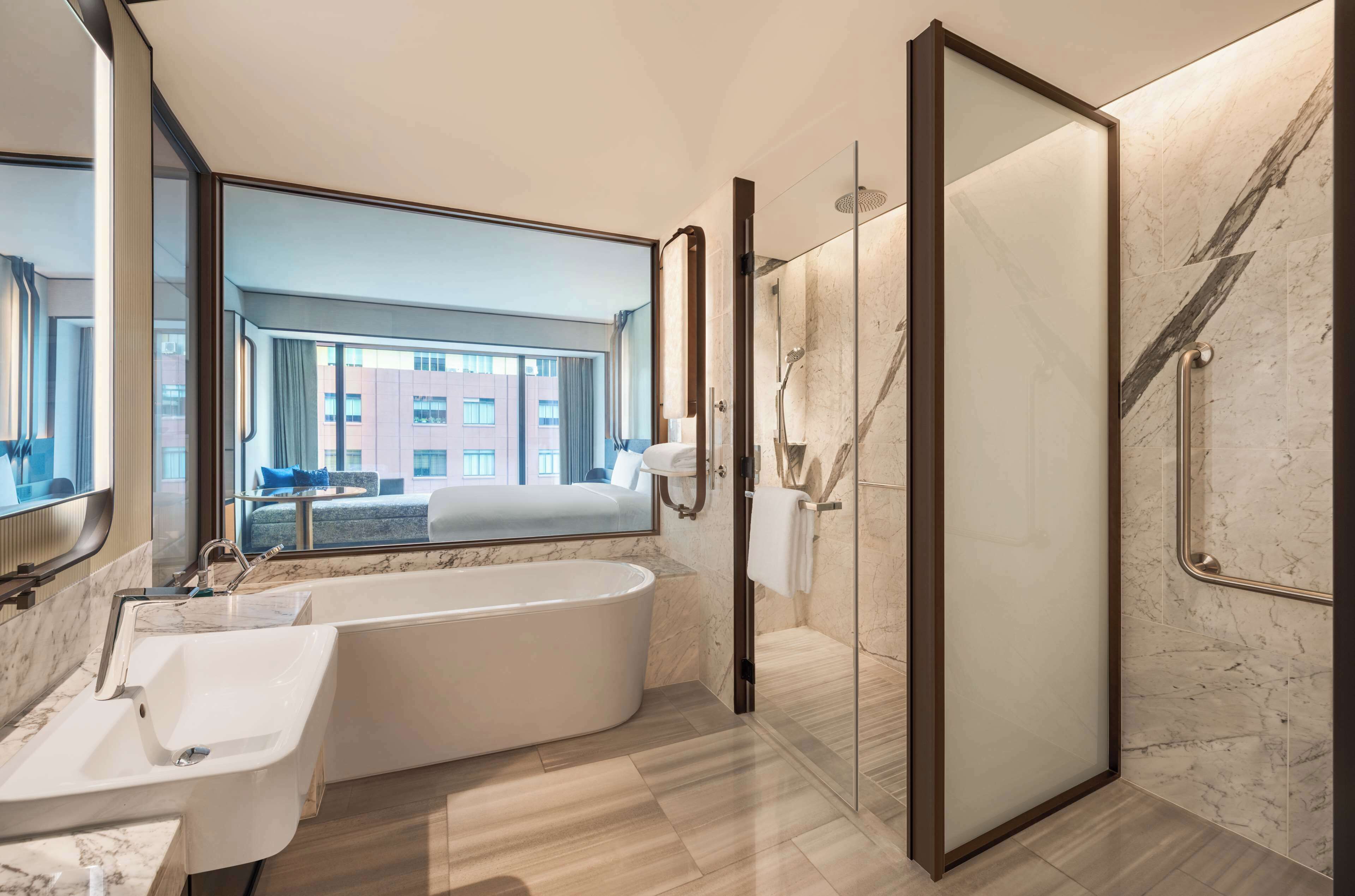 A modern bathroom with a large bathtub, a glass-enclosed shower, and a sink.