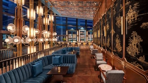 A luxurious interior with a long bar, blue seating, and ornate wall decorations. - Hilton Saigon (Ho Chi Minh City)