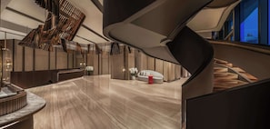 A modern interior with a curved staircase, a reception desk, and a seating area with a sofa and a small table.