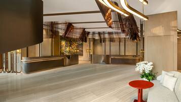 A modern lobby with a reception desk, seating area, and a decorative plant.