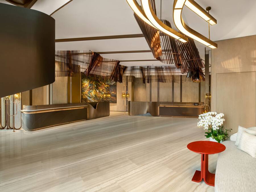 A modern lobby with a reception desk, seating area, and a decorative plant.