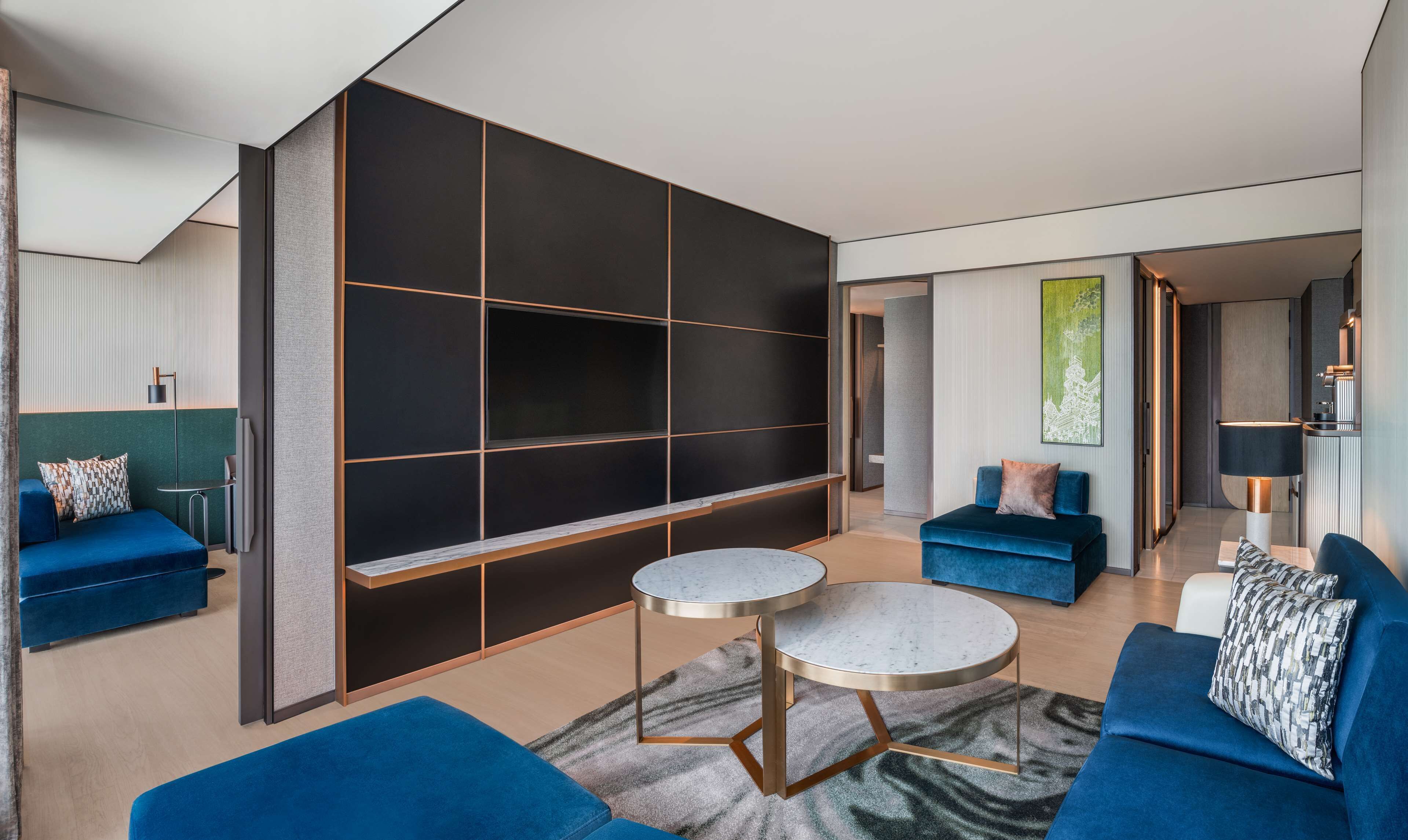 A modern living room with a large black sectional sofa, a round coffee table, and a TV mounted on the wall.