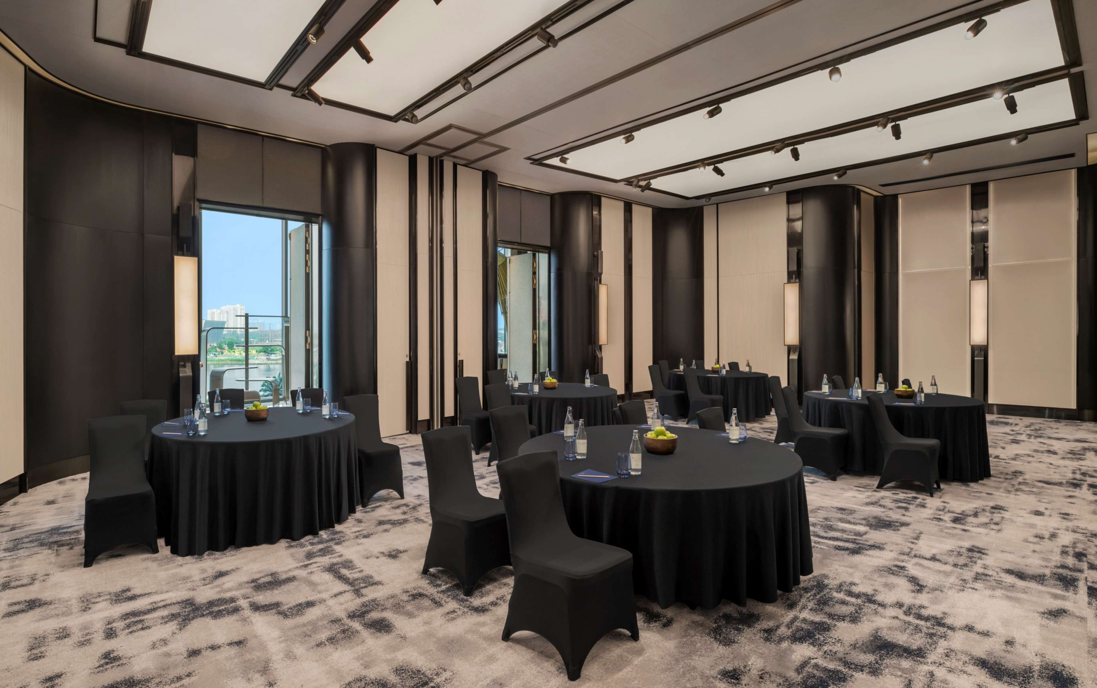 A conference room with round tables, chairs, and a carpeted floor.