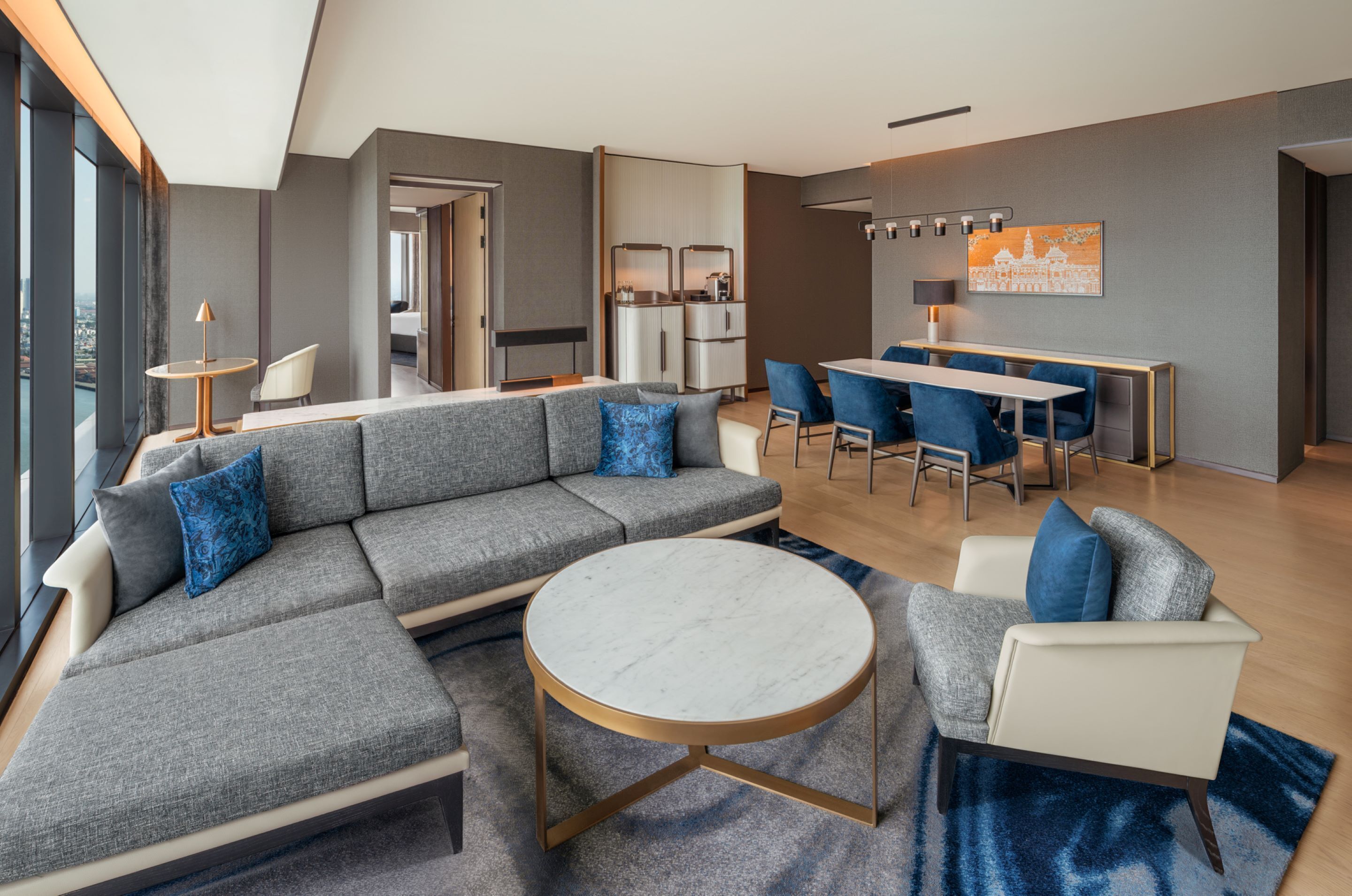 A modern living room with a sectional sofa, a round coffee table, and a dining area with blue chairs.