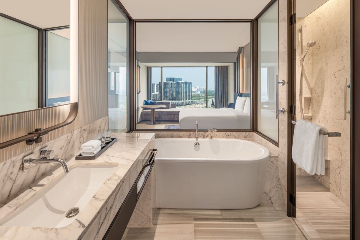 A modern bathroom with a large bathtub, a double sink, and a large mirror.