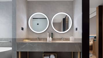 Une salle de bain moderne avec deux miroirs ronds, un comptoir en marbre et une étagère à serviettes.