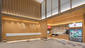A modern interior with a reception desk, vending machine, and wooden paneling. - Hilton Garden Inn Zigong High-Tech Zone (Zigong)