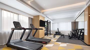 Un gimnasio de hotel con cintas de correr, una banca y equipo de pesas.