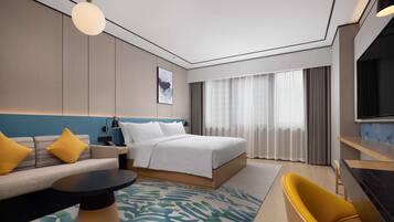A modern hotel room with a bed, sofa, and desk.