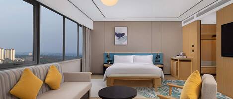 Ein modernes Hotelzimmer mit einem großen Bett, einer Couch, einem runden Tisch und Blick auf die Stadt.
