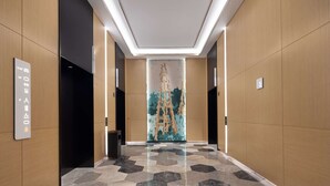 A modern hallway with a geometric patterned wall, a clean floor, and a ceiling with recessed lighting. - Hilton Garden Inn Zigong High-Tech Zone (Zigong)