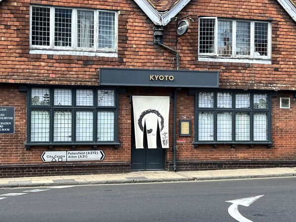 A two-story brick building with a sign reading "KYOTO". - Kyoto Rooms (Winchester)