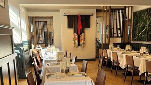 Un restaurante con mesas largas, sillas y un techo alto con iluminación empotrada.