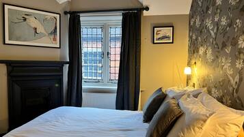 Un dormitorio con una cama grande, una chimenea y un ventanal con cortinas.