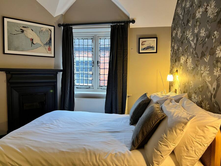 A bedroom with a large bed, a fireplace, and a window with curtains.