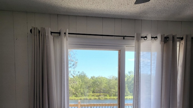 Un dormitorio con una cama grande, un banco y vistas a un balcón con mobiliario exterior.