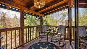 A wooden deck with rocking chairs and a star-patterned rug. - Epic Retreat I Pickleball I Basketball I Arcade I Putting Green I Air Hockey (Sevierville)