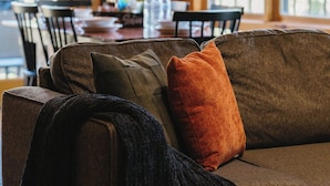 A cozy living room with a brown sofa, a dining table, and chairs. - Epic Retreat I Pickleball I Basketball I Arcade I Putting Green I Air Hockey (Sevierville)