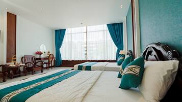 Habitación de hotel con dos camas, un escritorio con silla, un espejo y una ventana con cortinas.