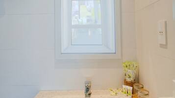 A bathroom with a white sink, a window above the sink, and a mirror.