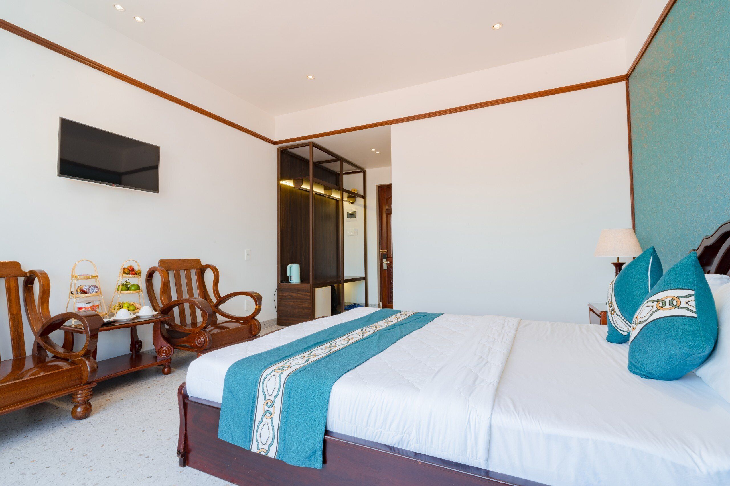 Un dormitorio con cama, sillas de madera, televisor y armario.