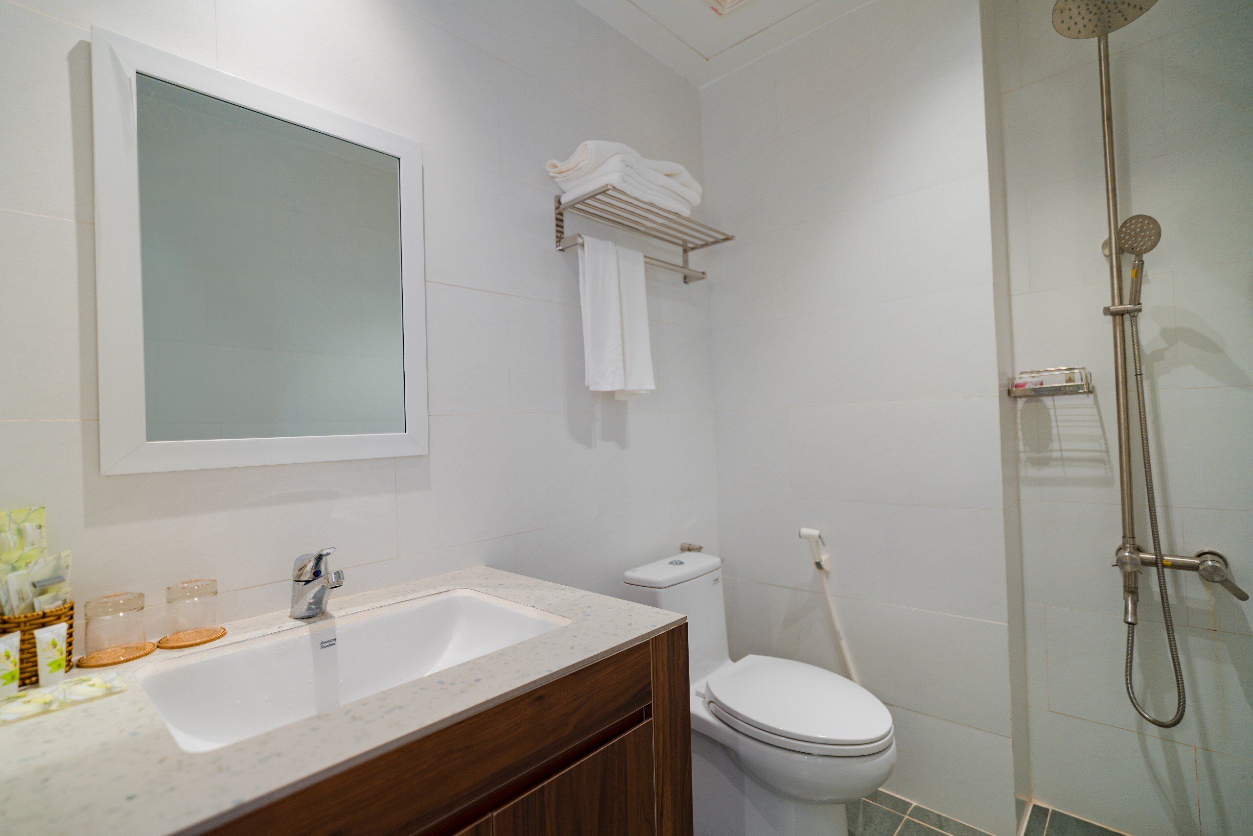 A modern bathroom with a sink, mirror, toilet, and shower.
